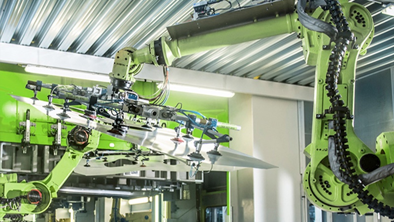 Industrial environment where two robots are assembling something onto a panel.