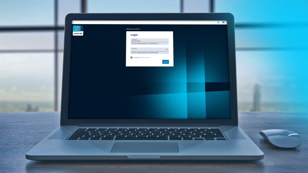 Open laptop on a table displaying a login screen on a dark blue background with the ctrlX OS app icon.