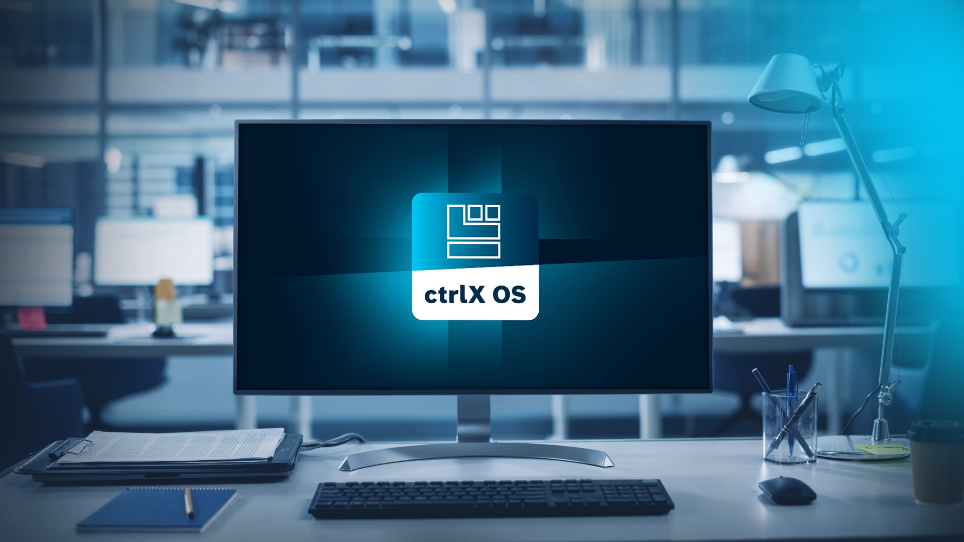 Monitor on an office desk in a workplace environment displaying the ctrlX OS app icon.